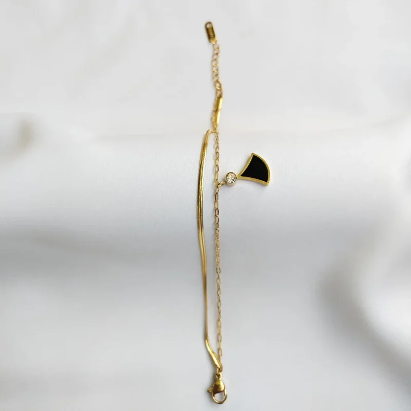 Elegant gold bracelet with black enamel charm and crystal